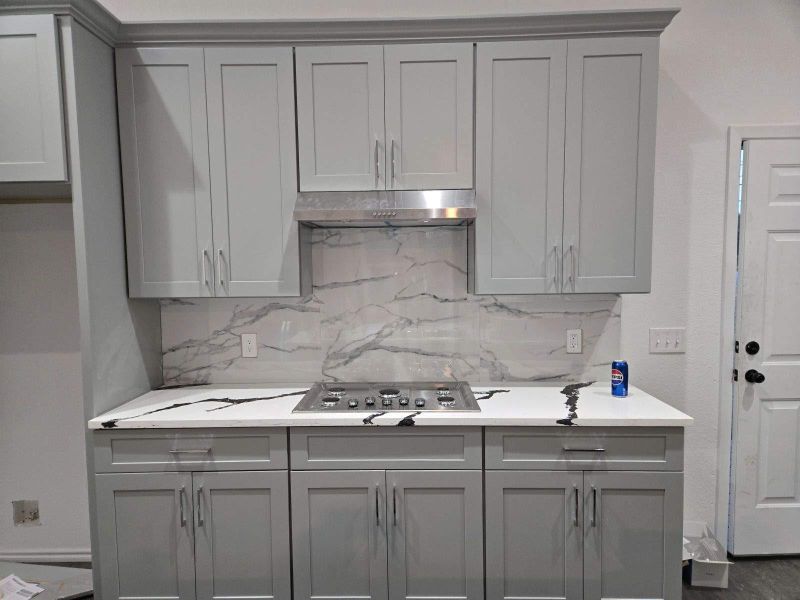 Kitchen with gray cabinetry, stainless steel, gas cooktop, and tasteful backsplash.