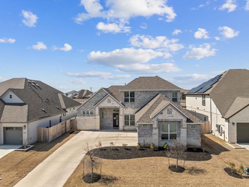 French country home featuring a garage, a shingled roof, stone siding, a residential view, and fence