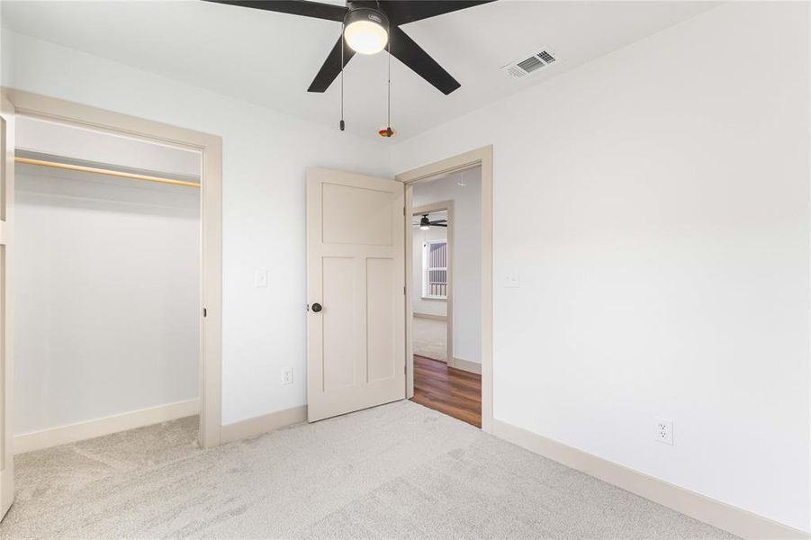 Unfurnished bedroom featuring light colored carpet, ceiling fan, and a closet Unfurnished bedroom featuring light colored carpet, ceiling fan, and a closet