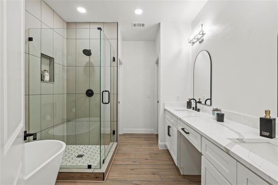 Bathroom with double vanity, a shower stall, recessed lighting, a soaking tub, and light wood-style flooring