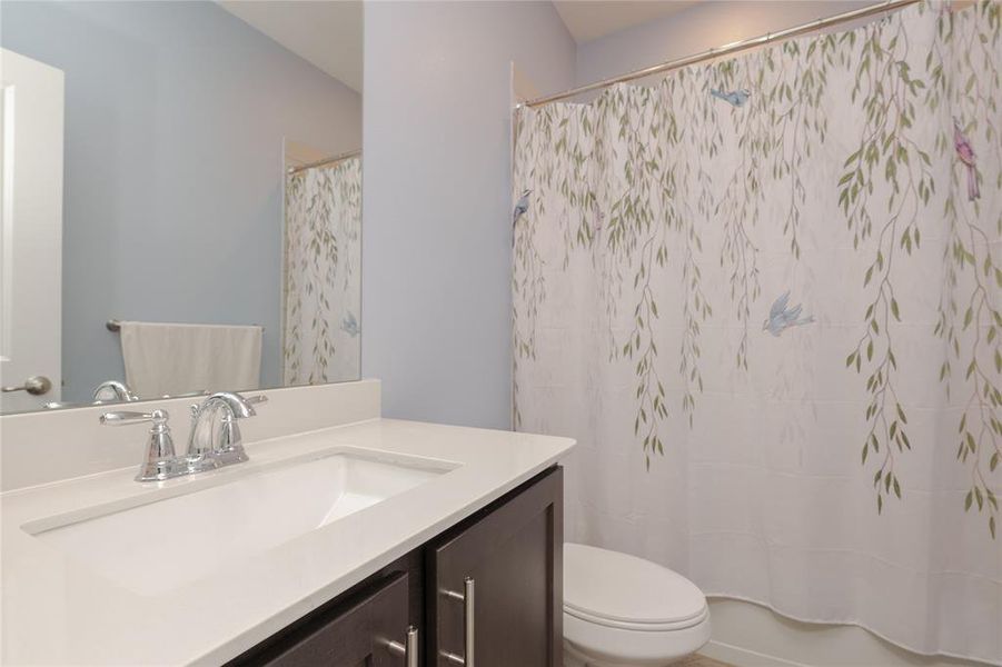 Full bathroom with shower / bath combo with shower curtain, vanity, and toilet