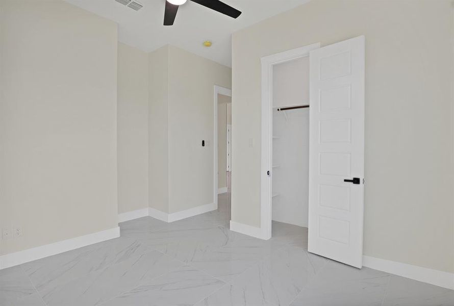 Unfurnished bedroom featuring ceiling fan, a spacious closet, and a closet