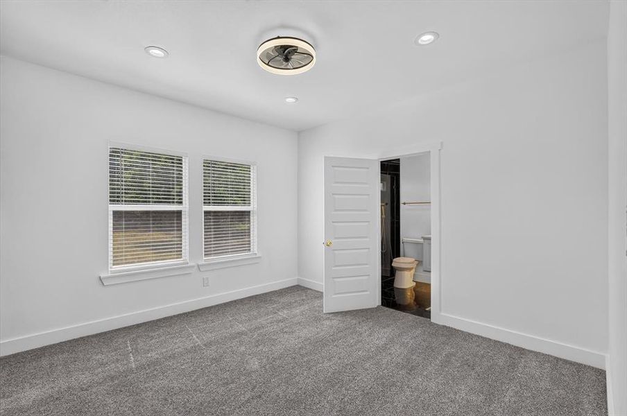 Room featuring gray carpeting, white walls, and two double-hung windows with blinds