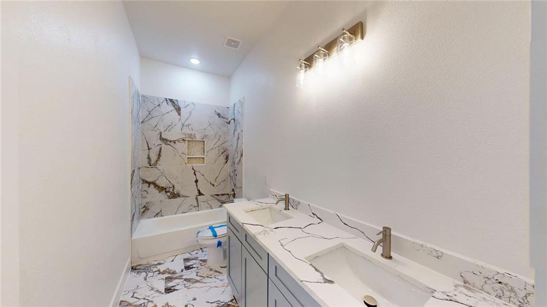 Bathroom with toilet, marble finish floor, visible vents, and a sink