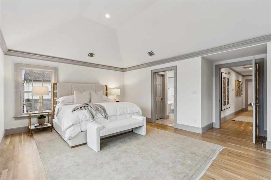 Bedroom featuring lofted ceiling, light wood-style floors, visible vents, and crown molding