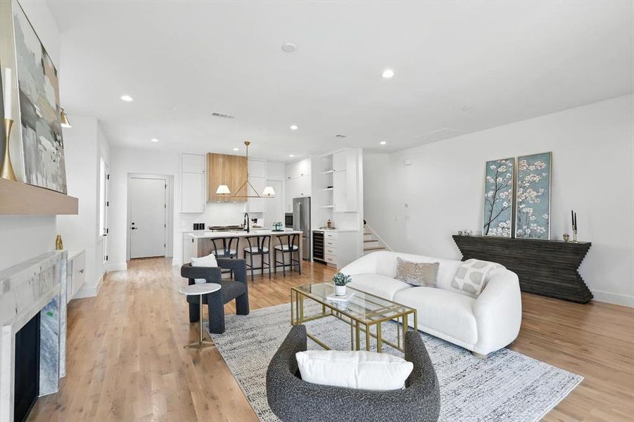 Living room featuring recessed lighting, light wood-style floors, a fireplace, stairway, and beverage cooler Living room featuring recessed lighting, light wood-style floors, a fireplace, stairway, and beverage cooler