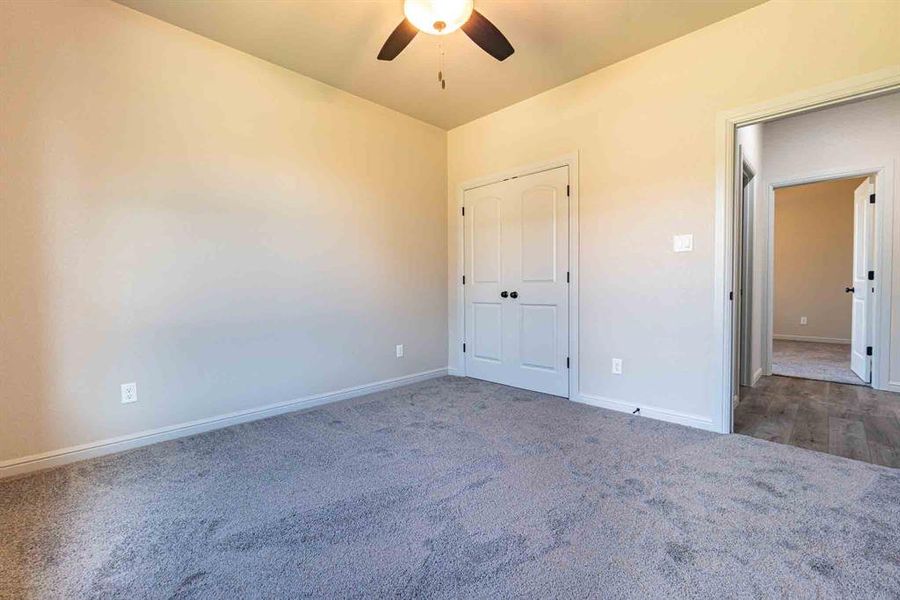 Unfurnished bedroom featuring ceiling fan, carpet, and a closet