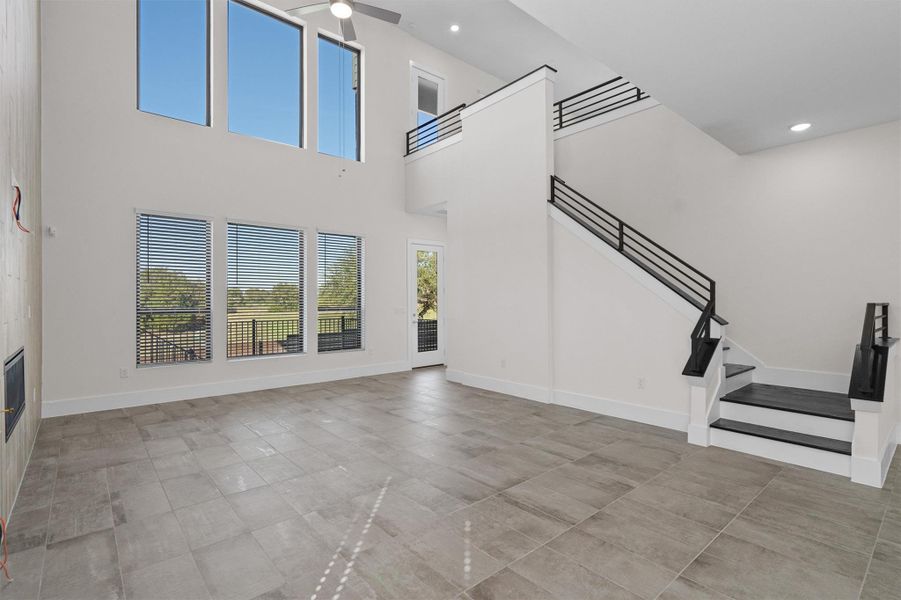 Unfurnished living room with recessed lighting, stairs, and a towering ceiling Unfurnished living room with recessed lighting, stairs, and a towering ceiling