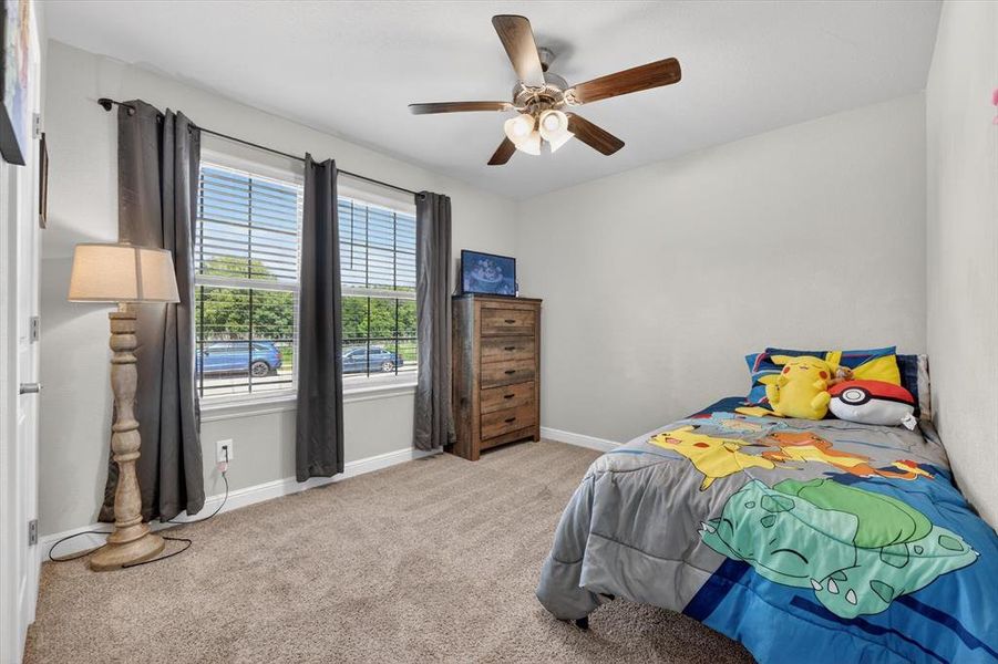 Carpeted room with a ceiling fan light fixture, two windows with blinds, and a built-in wooden dresser