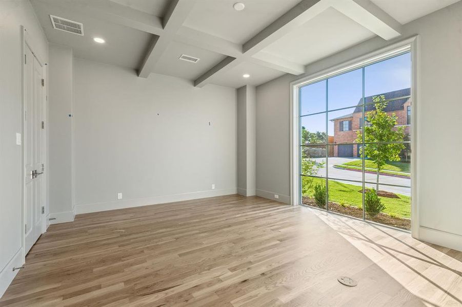 Spare room featuring light hardwood / wood-style flooring, beam ceiling, and coffered ceiling