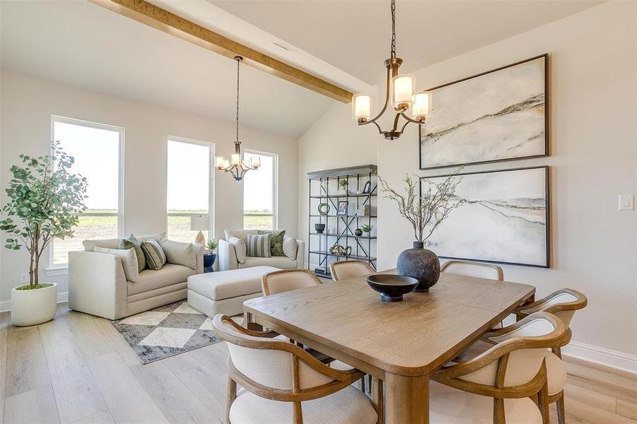 Dining room with lofted ceiling with beams, light wood-type flooring, and a notable chandelier