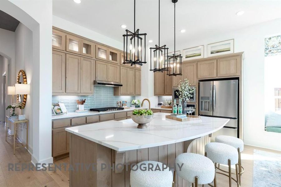 Kitchen with backsplash, a kitchen island with sink, a breakfast bar area, stainless steel appliances, and light stone countertops