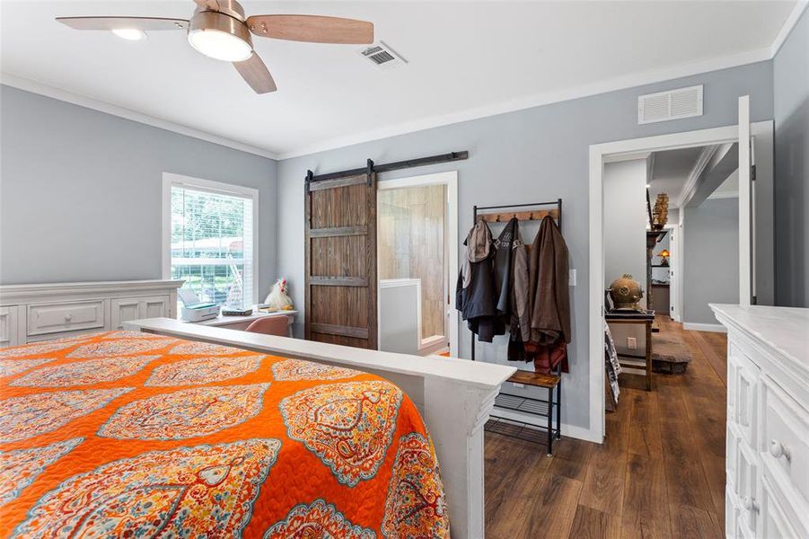 Looking toward the entry of the bedroom, you'll see the living room and hallway to the other two bedrooms, plus the barn door opens into the primary bathroom.