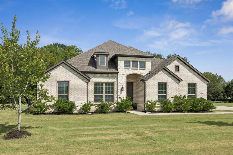 Traditional home featuring stone and brick siding and well maintained front yard.