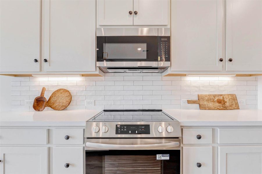 Soft-close cabinetry, brushed bronze hardware, and smooth glass-top range with exterior venting.