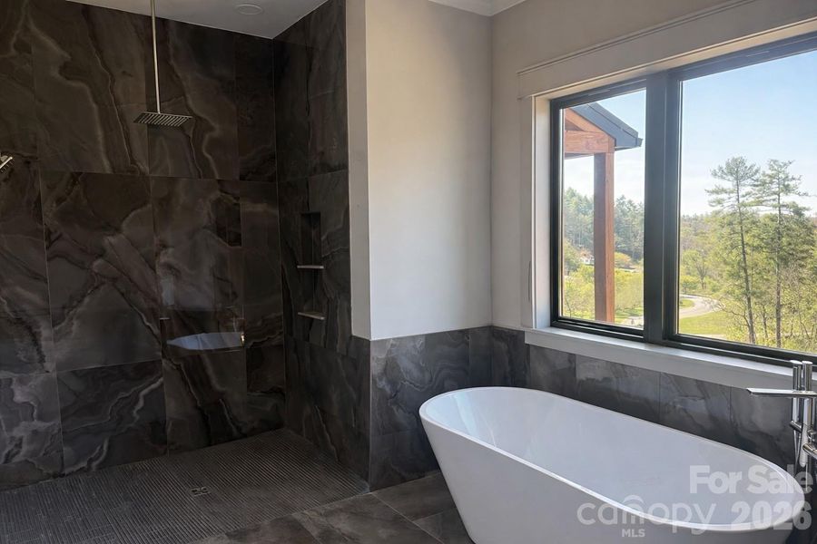 Primary bath featuring floor to ceiling tile, premium shower finishes and oversized soaking tub