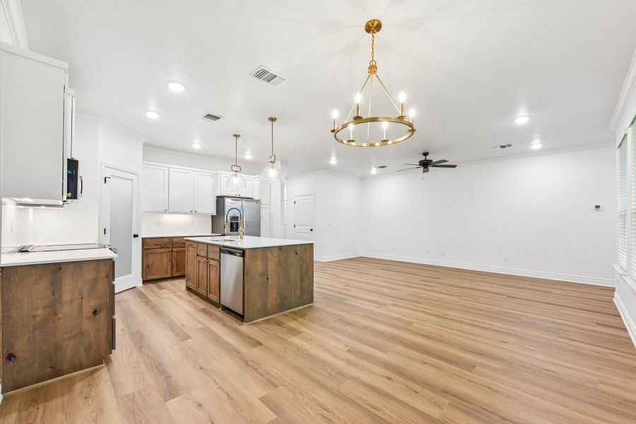 An open-concept living area featuring a central kitchen island and golden chandeliers provides an airy atmosphere. An open-concept living area featuring a central kitchen island and golden chandeliers provides an airy atmosphere.