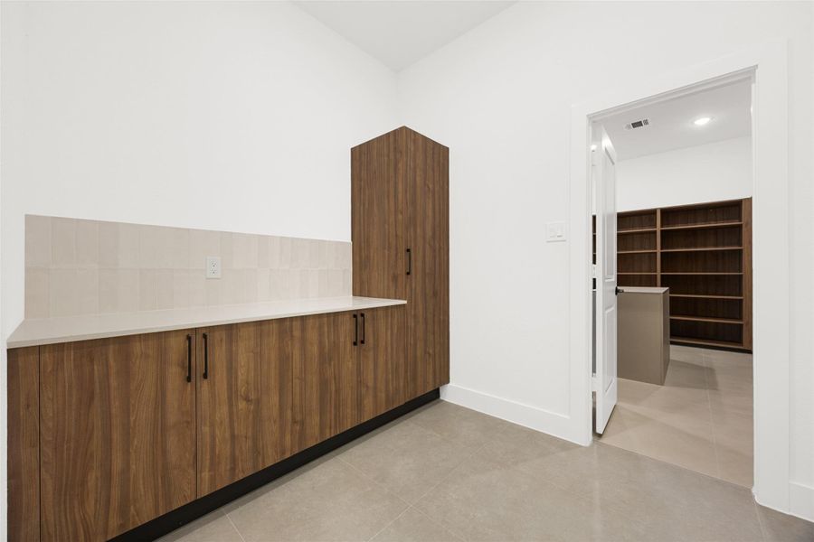 Additional custom designed cabinetry and workspace provide exceptional storage and organization in the laundry room.