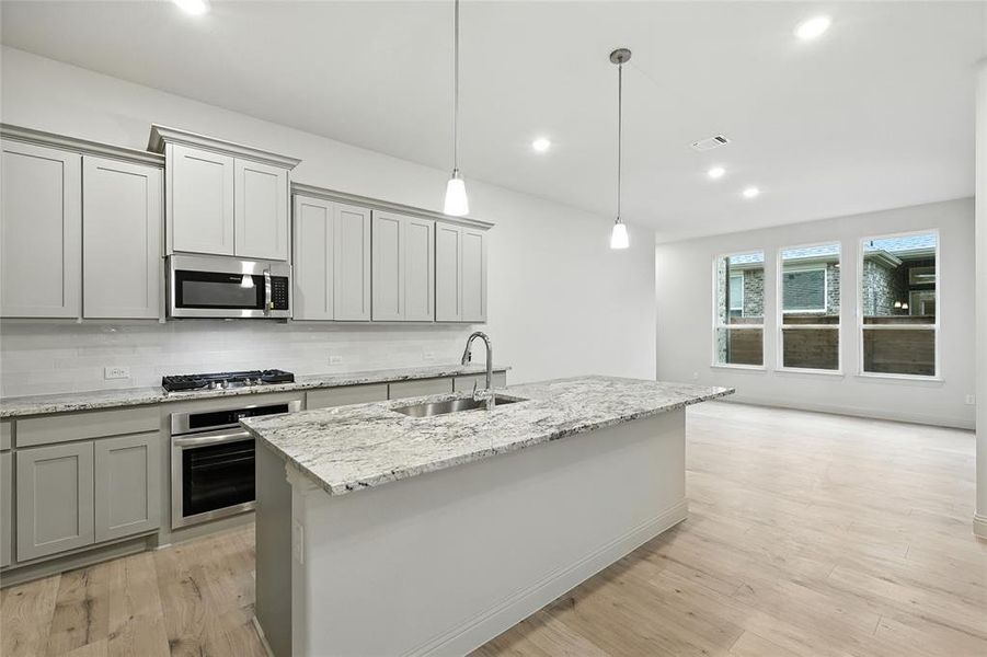 Kitchen featuring gray cabinets, stainless steel appliances, decorative backsplash, pendant lighting, and recessed lighting