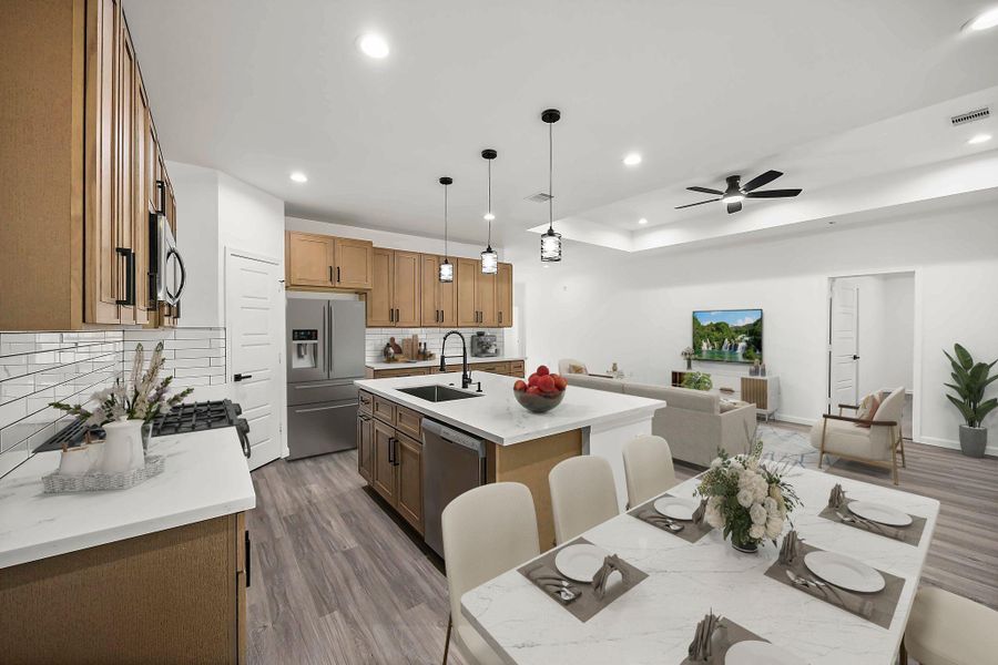 Spacious open-concept kitchen and living area featuring modern cabinetry, a large island with seating, and sleek stainless steel appliances.