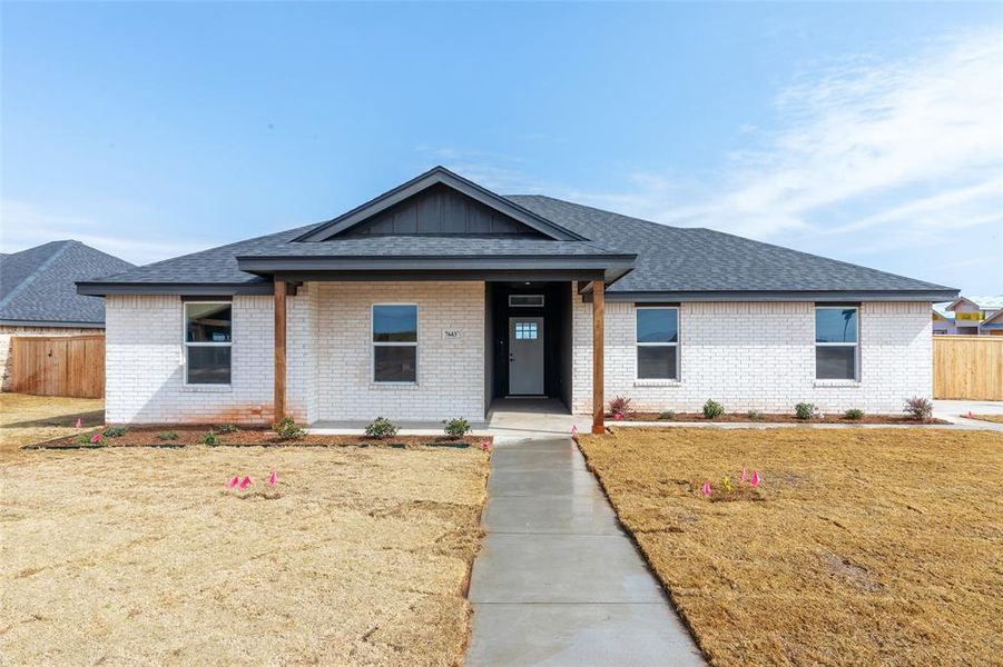 Single-story residence featuring a light brick exterior and dark shingle roofing