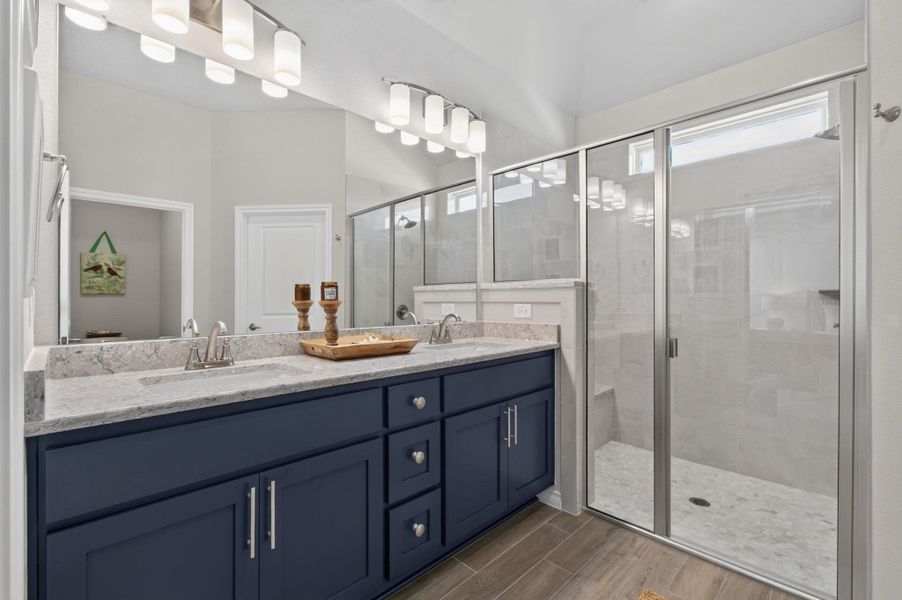 A well-lit primary bathroom features a spacious dual vanity with ample storage and a clear glass shower enclosure. A well-lit primary bathroom features a spacious dual vanity with ample storage and a clear glass shower enclosure.
