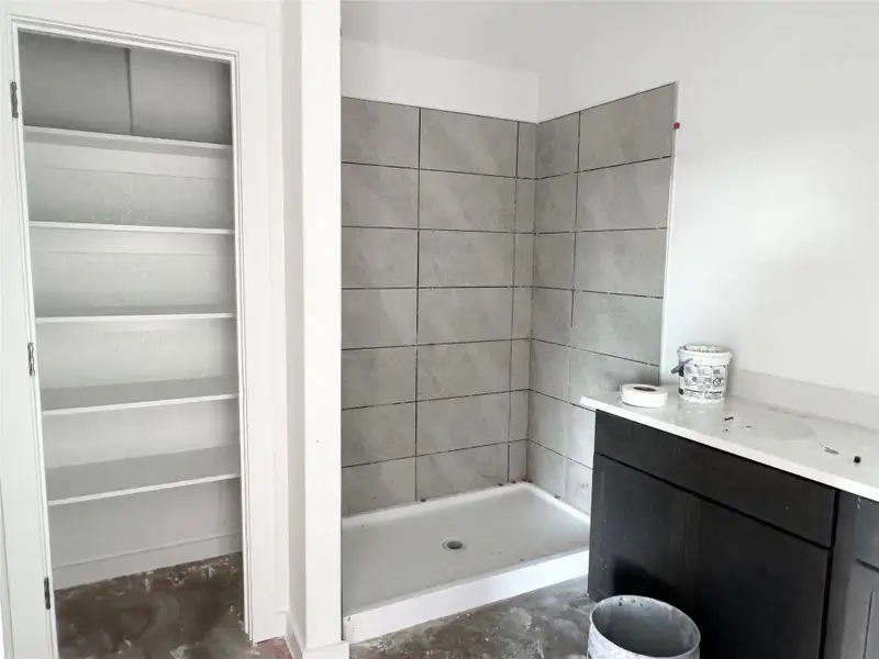 Full bath featuring a walk in closet, a shower stall, and vanity