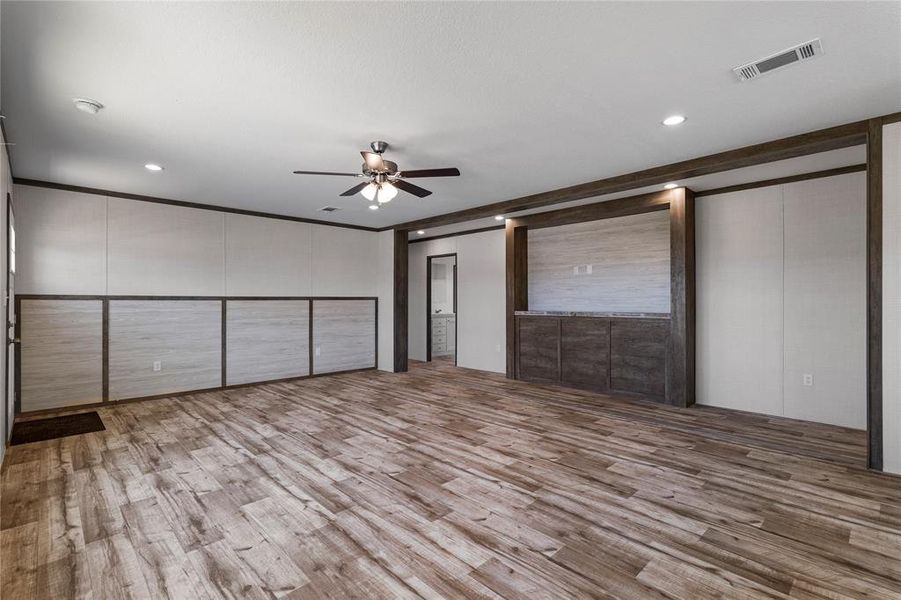 Unfurnished bedroom with light wood-style floors, ceiling fan, a decorative wall, recessed lighting, and crown molding