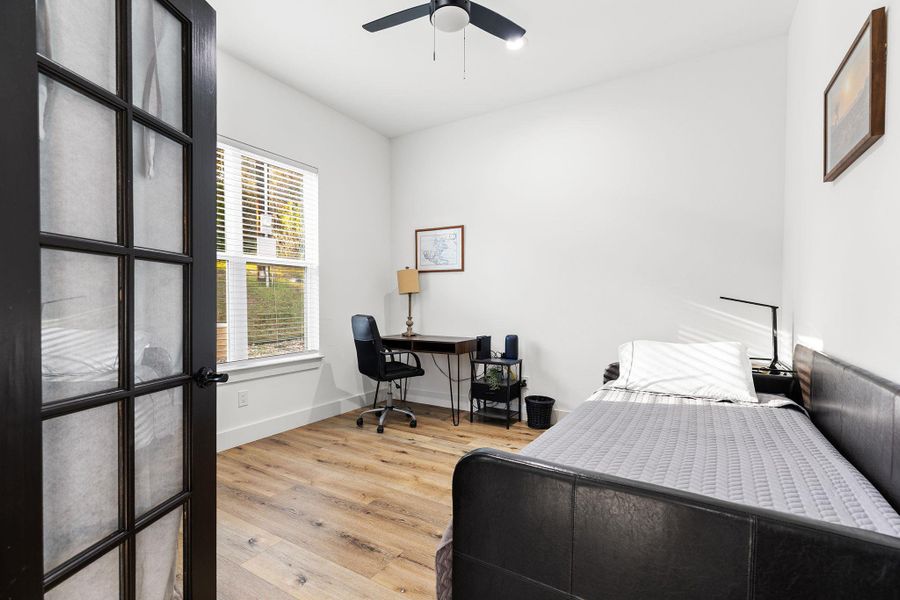 Bedroom featuring light wood-style floors, an office area, and a ceiling fan
