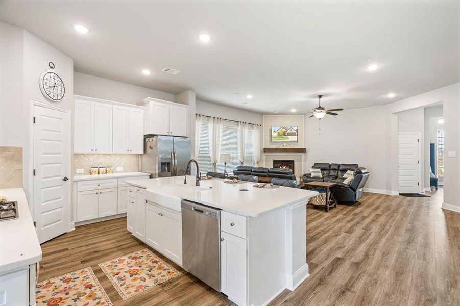 Open-concept living space with wood-finish flooring, recessed lighting, and a neutral color palette Open-concept living space with wood-finish flooring, recessed lighting, and a neutral color palette