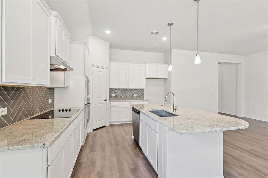 Kitchen with a kitchen island with sink, light hardwood / wood-style flooring, tasteful backsplash, and sink