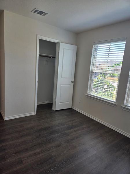 Unfurnished bedroom featuring dark hardwood / wood-style flooring and a closet