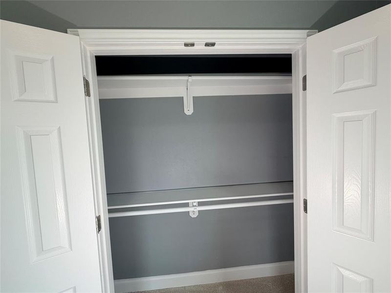 Dual panel doors opening to a closet featuring two storage rods and a top shelf Dual panel doors opening to a closet featuring two storage rods and a top shelf