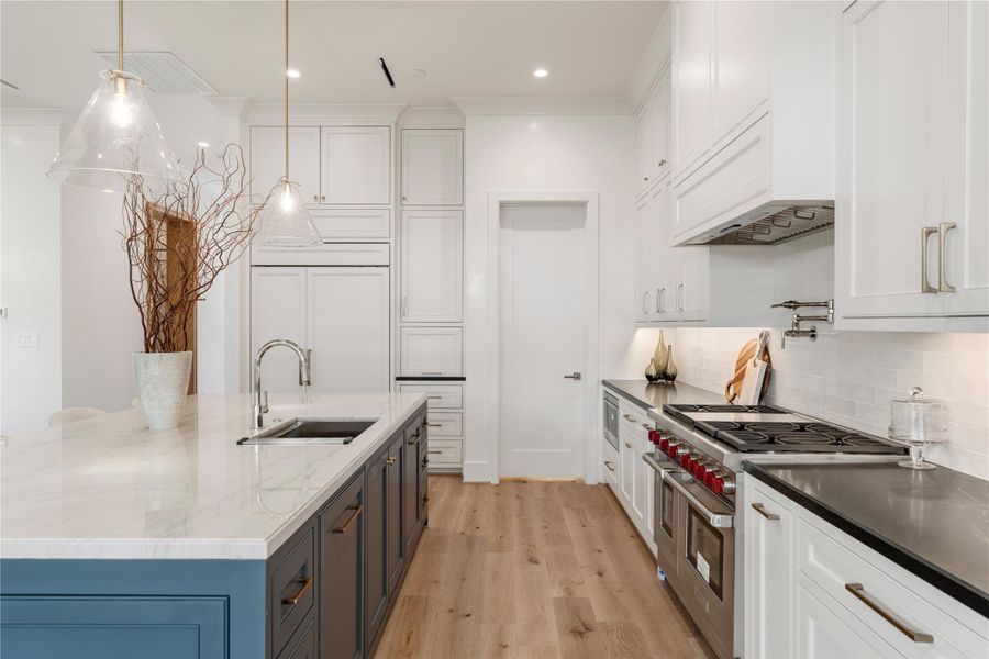 A closer look at the stainless appliances. The restaurant-quality rangehood is encased in white trim for a seamless appearance. The Wolf microwave and gas range with infrared griddle gleam in the sunlight! A pot-filler will make pasta prep a breeze.