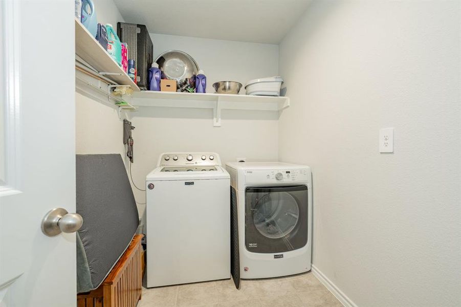 Clothes washing area featuring laundry area, light tile patterned floors, baseboards, and independent washer and dryer