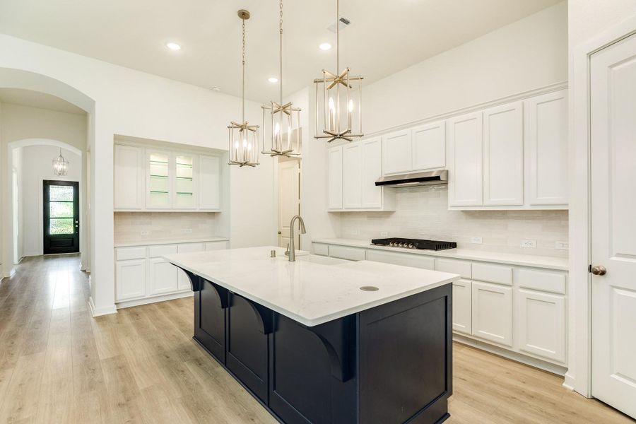 Butler's pantry featuring elegant glass-front cabinetry and convenient access to the two secondary bedrooms situated privately behind the kitchen.