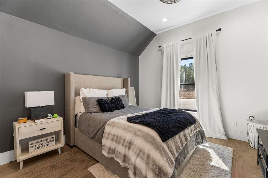 Bedroom featuring lofted ceiling, wood finished floors, and recessed lighting Bedroom featuring lofted ceiling, wood finished floors, and recessed lighting