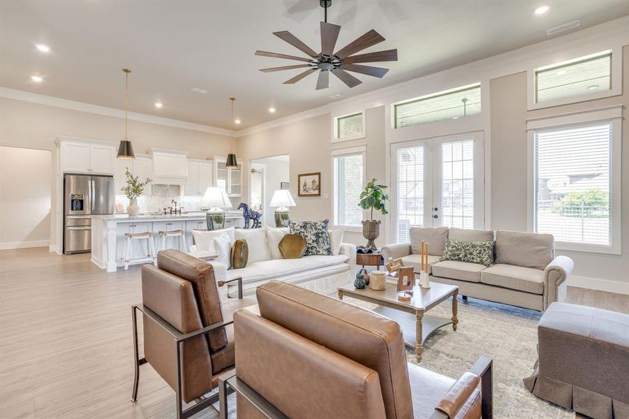 Open-concept living area featuring wood-finish flooring, a contemporary ceiling fan, recessed lighting, and crown molding