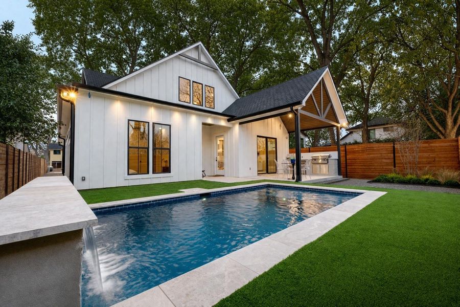 The property features a swimming pool with a waterfall, surrounded by artificial turf and a paved patio area