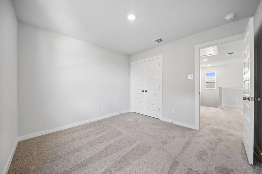 A spacious, naturally illuminated room features plush carpeting and a large bi-fold closet, offering comfort and convenience. A spacious, naturally illuminated room features plush carpeting and a large bi-fold closet, offering comfort and convenience.