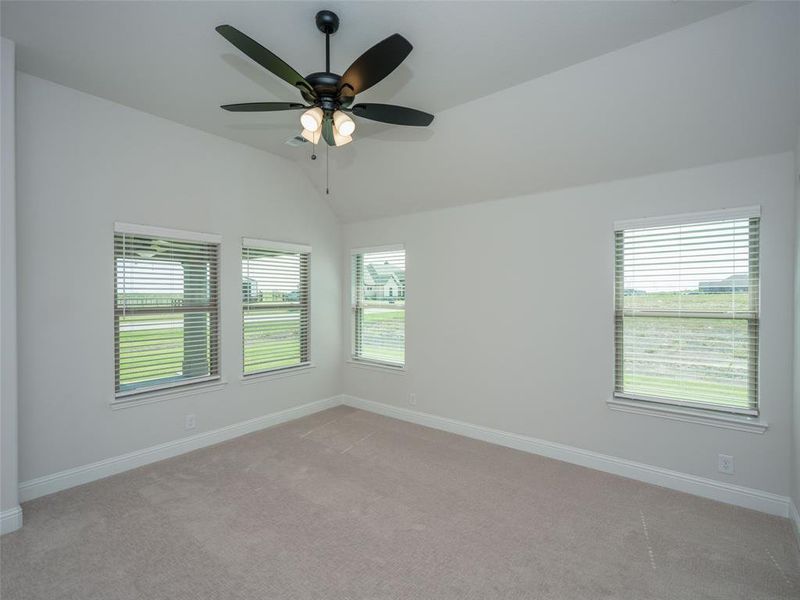 Unfurnished room with carpet flooring, lofted ceiling, and ceiling fan Unfurnished room with carpet flooring, lofted ceiling, and ceiling fan