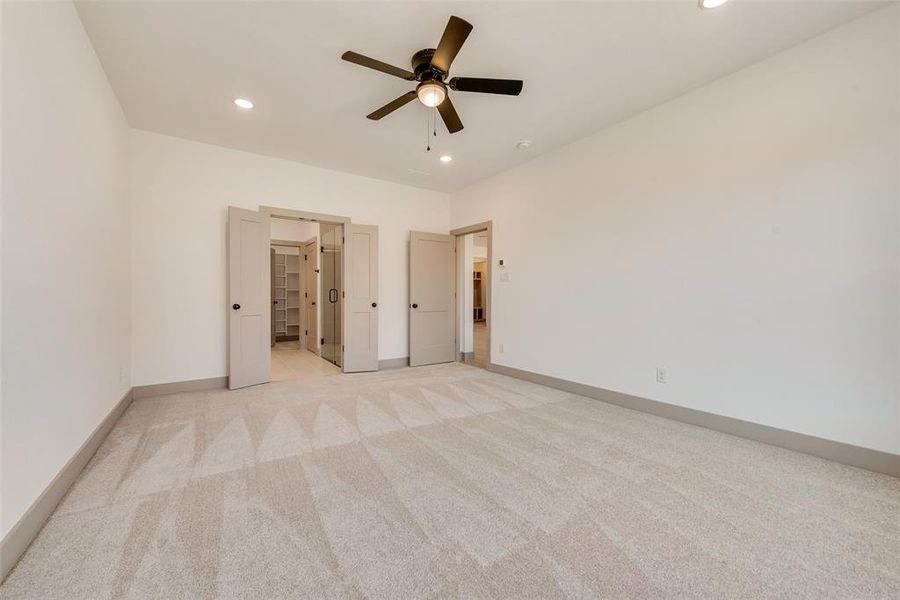 Unfurnished bedroom with ceiling fan, light colored carpet, and a spacious closet