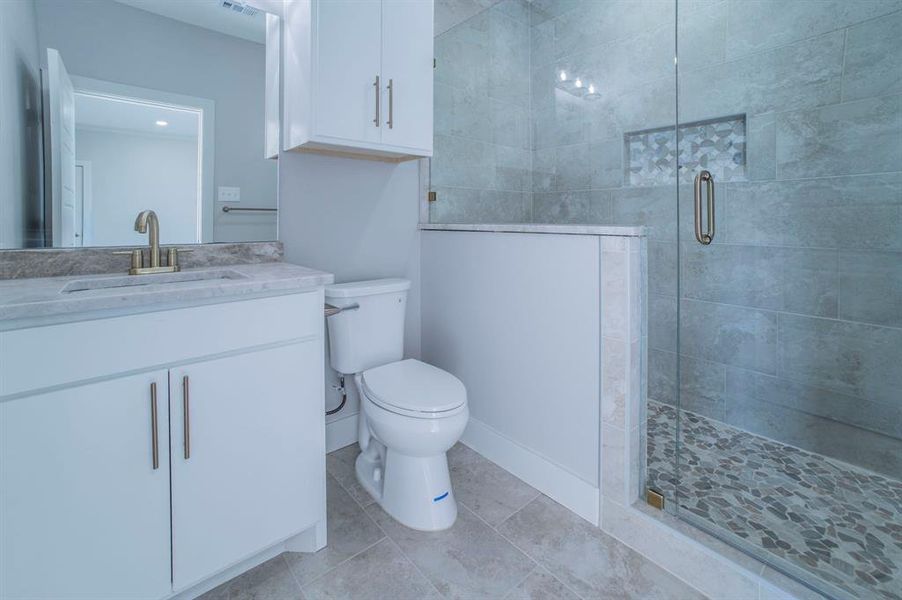 Full bath with vanity, a stall shower, and light tile patterned floors