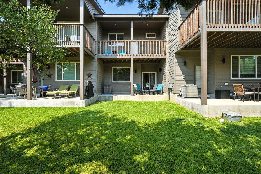 Rear view of townhome featuring a patio area and a lawn Rear view of townhome featuring a patio area and a lawn