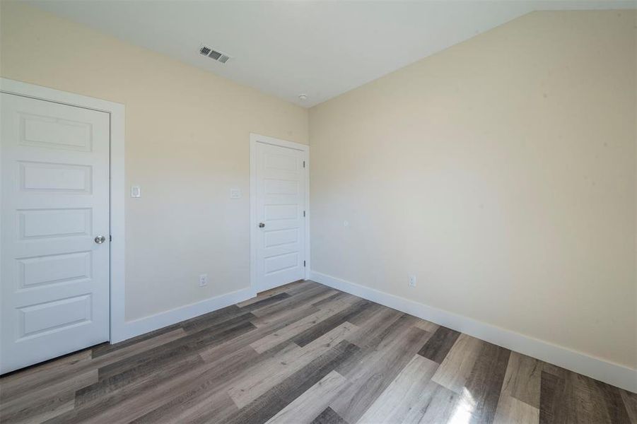 Empty room featuring baseboards, visible vents, and wood finished floors