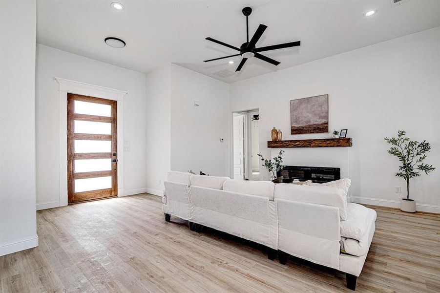 Living room with light wood-style floors, ceiling fan, and recessed lighting