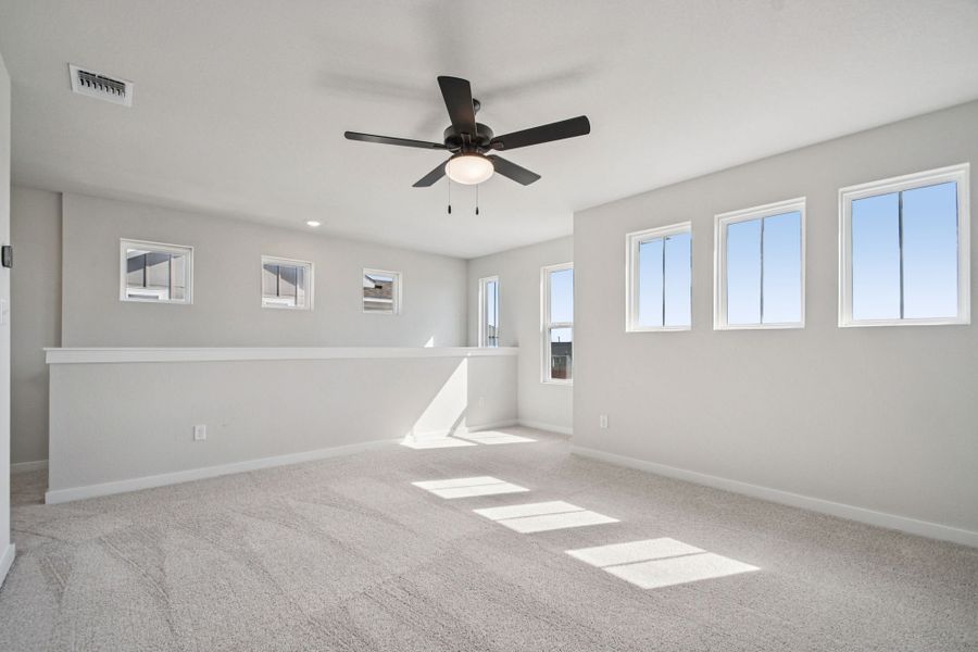 A room with a ceiling fan and a white wall with a light.