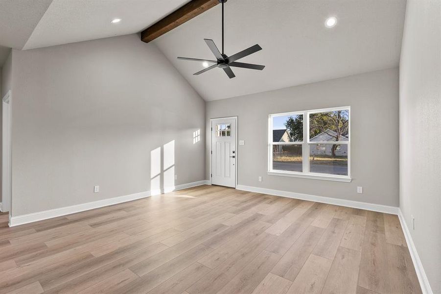 Unfurnished living room featuring beam ceiling, ceiling fan, high vaulted ceiling, recessed lighting, and light wood-type flooring Unfurnished living room featuring beam ceiling, ceiling fan, high vaulted ceiling, recessed lighting, and light wood-type flooring