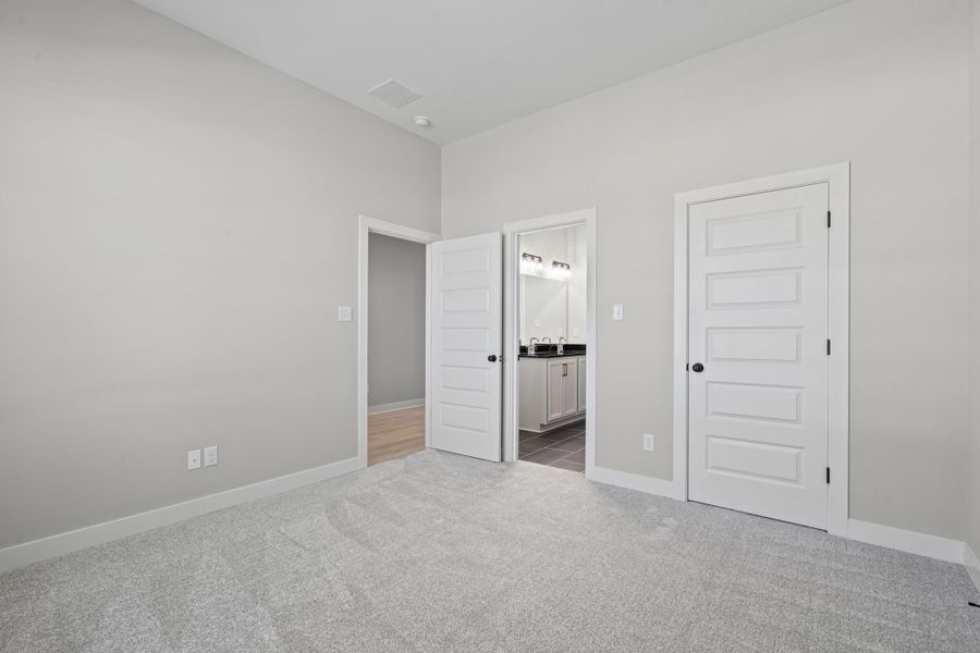 Unfurnished bedroom with light colored carpet, a closet, and connected bathroom