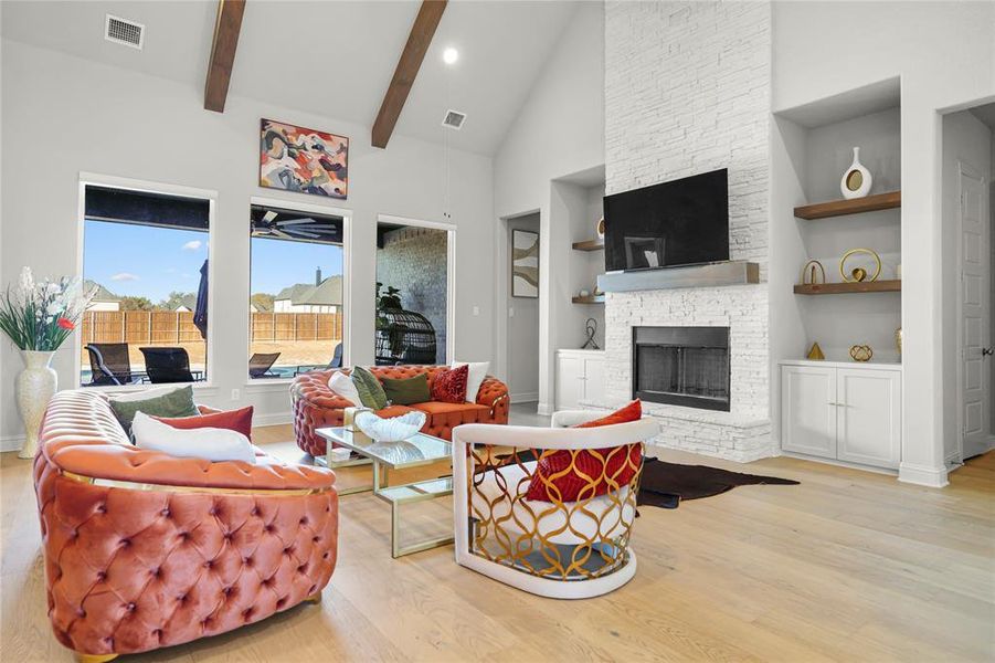 Living area featuring high vaulted ceiling, a fireplace, light wood finished floors, beamed ceiling, and built in shelves Living area featuring high vaulted ceiling, a fireplace, light wood finished floors, beamed ceiling, and built in shelves